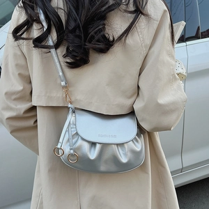Detail of silver pleated crossbody bag with gold hardware and logo on beige trench coat