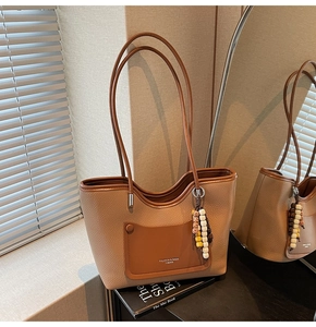 Dettaglio borsa tote in pelle caramello con grana litchi e ciondolo di perline