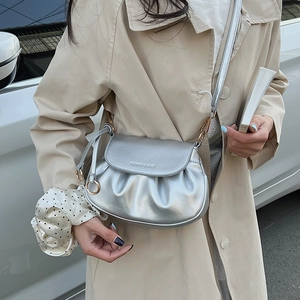 Chic silver pleated crossbody bag styled with a beige trench coat for a modern city look