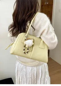 Detail of beige faux leather tote bag featuring a metal ring and plush doll charm