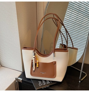 Dettaglio della borsa tote bicolore con trama in pelle martellata e pendente con perle