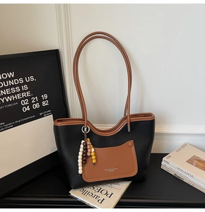 Dettaglio della borsa tote vintage in pelle a contrasto con charm di perline