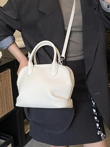 Chic off-white lychee pattern shell bag with top handles and adjustable strap on model