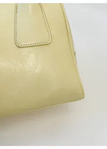 Close-up of beige leather texture and reinforced stitching on a stylish underarm bag
