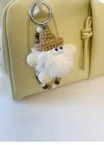 Detail of cute long-hair plush elf charm with knit hat on a yellow leather shoulder bag