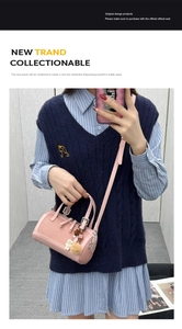 Detail of pink cylindrical crossbody bag with bear charm and pompom on model