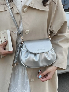 Silver metallic pleated square bag with gold buckle on model with trench coat