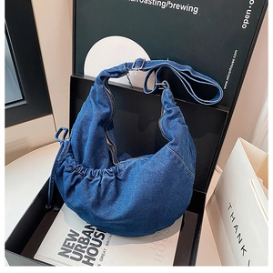 Detailansicht einer blauen Denim-Hobo-Tasche mit Silber-Reißverschluss in einer Geschenkbox