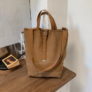 Détail d'un sac cabas en toile camel avec bandoulière réglable sur table en bois