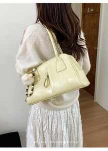 Minimalist cream yellow tote bag detail with decorative plush ball charm on model