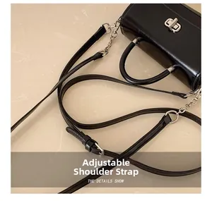 Detailed view of adjustable leather shoulder strap and silver hardware buckle on a black handbag