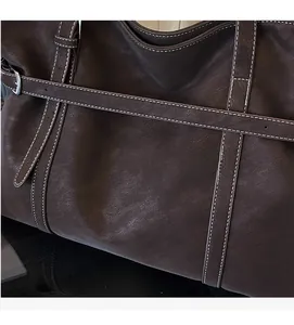 Detail of dark brown leather tote bag with contrast stitching and soft pebbled texture