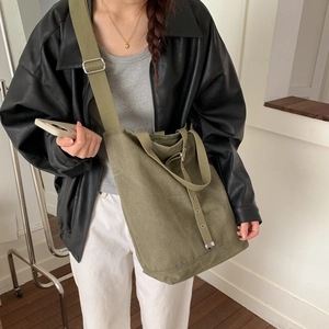 Détail du sac seau en toile vert armée avec bandoulière large et boucles en métal