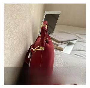 Detailed shot of burgundy bucket bag with high-quality gold hardware on bed