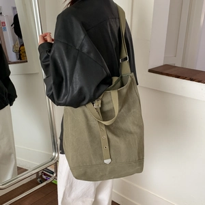 Vue latérale du grand sac cabas en toile vert olive porté par un mannequin avec détails