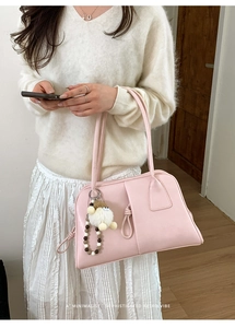 Pink retro faux leather handbag with cute plush charm and bead detail on a model