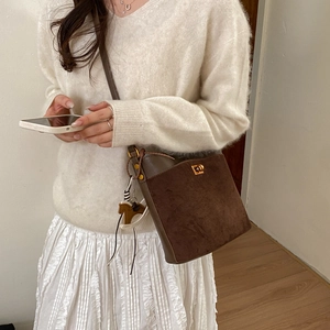 Detail of dark brown suede bucket bag with gold twist lock and horse charm decoration