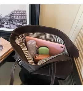 Interior view of large brown tote bag with striped lining and contrast stitching details