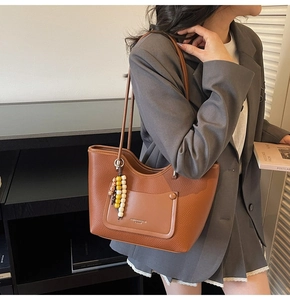 Dettaglio della borsa tote in pelle marrone con ciondolo di perline colorate