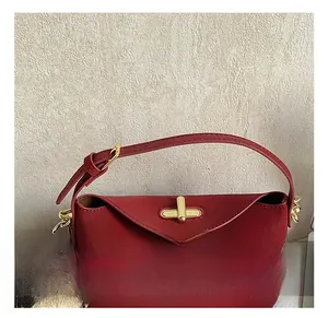 Close-up of a red leather bag with gold buckle and cute cream plush bear charm