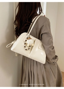 Detail of cream oversized tote bag with bead pendant shown on a model's shoulder