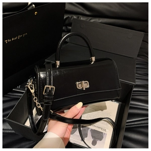 Detail of black patent leather handbag featuring a silver twist lock and gift packaging