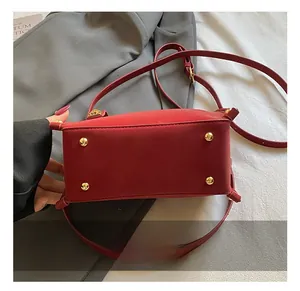 Close-up of red shoulder bag base featuring four protective golden metal feet studs