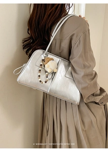 Silver metallic tote bag with unique doll pendant on model in a retro vibe outfit