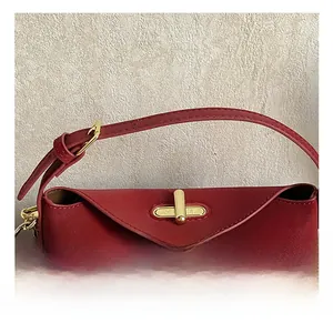 Close-up of golden metal twist-lock on red litchi leather handbag with polka dot pendant