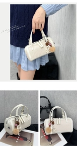 Detail of cream woven Boston handbag with plush bear charm and dual zipper on magazines