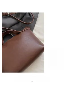 Close-up of the brown grainy leather texture and stitching on the tote bag