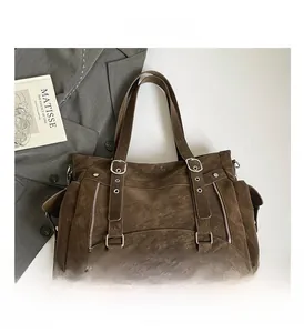 Detail of vintage brown tote bag featuring decorative straps and silver metal buckles