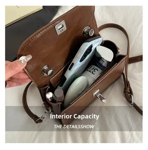 Detailed interior of vintage brown crossbody bag showing storage for phone and cosmetics