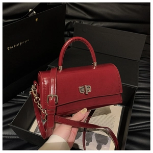 Detailed close-up of glossy burgundy patent leather handbag with silver metallic twist lock