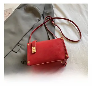 Detail show of red leather crossbody bag with gold twist lock and metallic studs