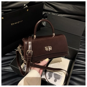Detail of dark brown patent leather handbag with metal twist lock in a luxury gift box