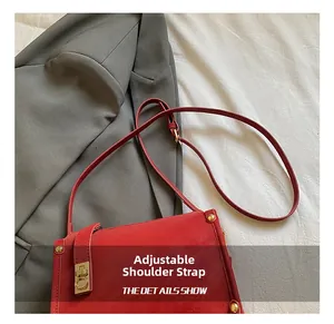 Detail showing the adjustable shoulder strap and gold hardware of the red crossbody bag
