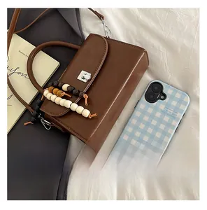 Close-up of retro brown leather crossbody bag with silver buckle and beaded handle detail