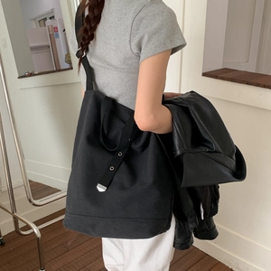 Détail du sac seau en toile noire avec œillets argentés et large bandoulière