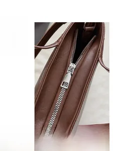 Close-up of smooth silver metal zipper on a premium brown leather shoulder bag