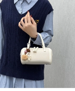 Detail of off-white canvas and leather Boston bag with a cute bear charm and tassel