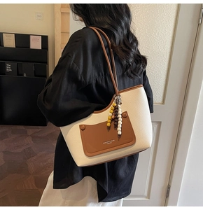 Dettaglio della borsa tote crema con bordo marrone e accessorio di perline di legno vintage