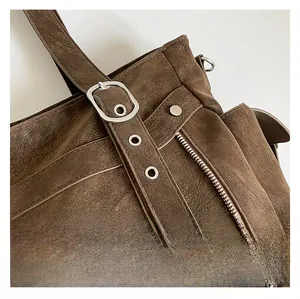 Detail of vintage brown tote bag showing aged texture leather and silver hardware buckles