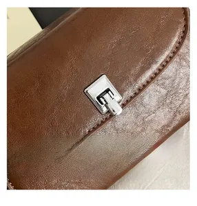 Close-up of caramel brown leather handbag with polished silver metal twist lock detail