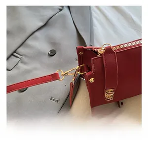 Detailed close-up of premium gold hardware hooks and red leather texture on a shoulder bag