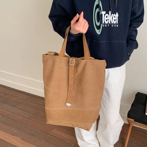 Détail du sac seau en toile avec sangles verticales, boucles argentées et garniture en métal