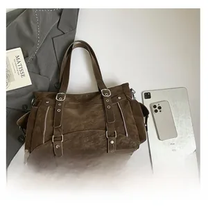 Detail view of large dark brown suede tote bag with decorative buckles and metal zippers
