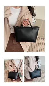 Close-up of minimalist black leather handbag showing smooth matte texture and metal hardware