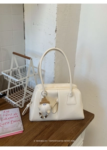 Close-up of a cream retro handbag with a plush charm accessory on a vintage table