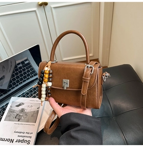 Brown leather crossbody bag with metal buckle and decorative wood bead keychain